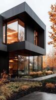 Modern architecture with large windows and reflective glass, surrounded by autumn foliage and landscaped garden, creates sleek and inviting atmosphere photo