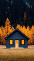 cozy wooden house surrounded by vibrant autumn trees, showcasing striking contrast between dark exterior and bright orange foliage. serene landscape invites tranquility and warmth photo