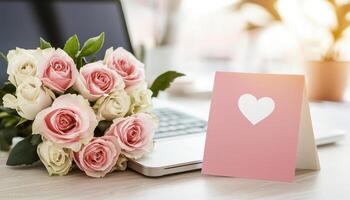 beautiful bouquet of pink and white roses sits beside laptop, with heart shaped card, creating happy atmosphere for anniversary celebration work photo