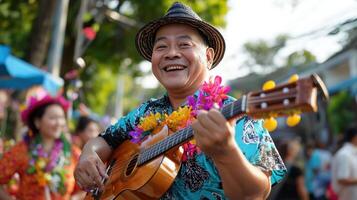 Man playing guitar, smiling, wearing hat and floral shirt at festival photo