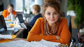 young woman in orange sweater smiles at camera, surrounded by paperwork and colleagues in busy office environment photo