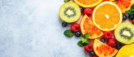 Fresh cut fruits including oranges, kiwi, raspberries, and mint leaves arranged beautifully on light background photo
