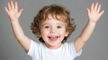 Happy toddler raising and smiling hands on gray background photo