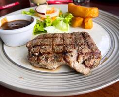 A plate of food with a side of salad and a side of sauce photo