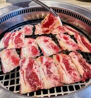 Delicious raw beef slices are being cooked on a grill photo
