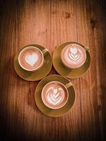 Three cups of coffee with latte art on wooden table photo