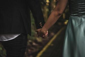 Couple holding hands intimately in a forest, expressing love and connection photo