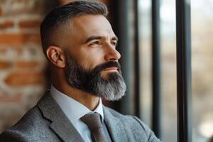 Professional man gazing thoughtfully out of a window in a stylish urban setting with brick wall backdrop photo