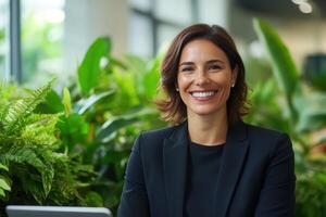Smiling businesswoman in a modern office surrounded by greenery during a workday photo