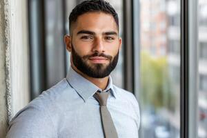 Professional man poses confidently in modern office with large windows and urban view photo