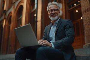 Man working on laptop outside in urban setting during daylight hours photo