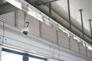 Security camera mounted on industrial ceiling in a modern building photo