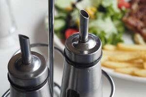 Condiment holders beside a fresh salad and fries on a dining table photo
