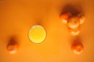 Fresh juice and oranges displayed on a vibrant orange background photo