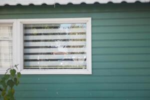 Green house with window displaying striped curtains and reflections photo