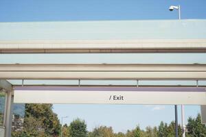 Exit sign located in public transport area under clear blue sky photo