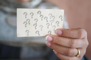 Holding a card with multiple question marks in a thoughtful moment photo