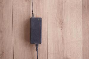 Power adapter resting on wooden surface with cable attached photo