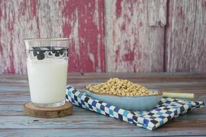 Soy milk in a glass with soybeans on a rustic wooden table photo