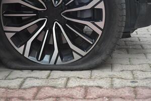 Flat tire on a stylish car parked on a cobblestone street photo