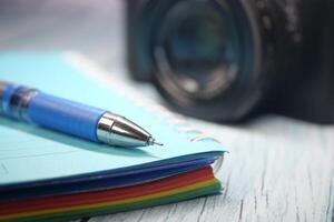 A colorful notebook and pen are placed near a camera on a desk photo