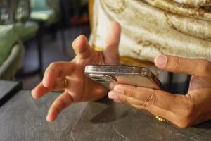 Engaging with a smartphone while seated in a cozy cafe setting photo