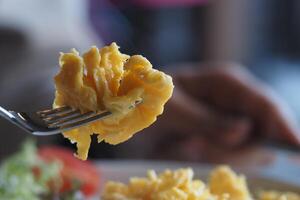 Scrambled eggs on a fork close to a fresh breakfast plate photo