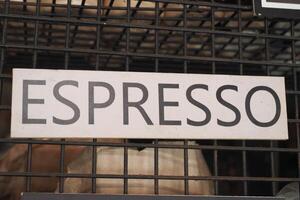 Sign displaying espresso in a bustling cafe setting photo