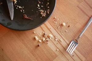 Crumbs and utensils left on a wooden table after a meal photo