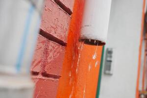 Water dripping from a rain gutter on a colorful wall photo