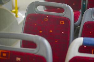 Red upholstered bus seats arranged in a public transport setting photo
