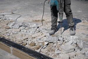 Construction worker using jackhammer on pavement at a work site photo