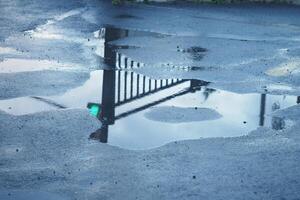 Puddle reflecting a fence and light after rain in a parking lot photo