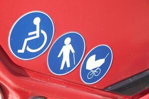 Various accessibility symbols displayed on a red vehicle's surface photo
