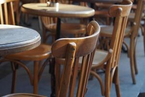 Rustic wooden chairs and tables in a lively cafe setting photo