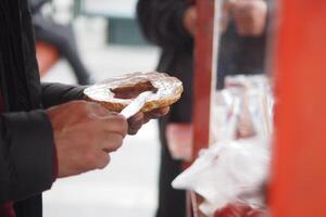 Person preparing a snack with a spread at a street cart photo