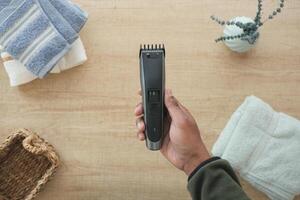 Hand holding a hair clipper in a tidy bathroom setting photo