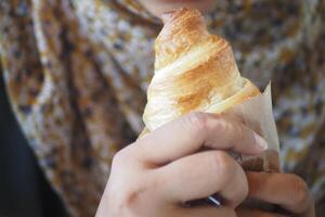 Enjoying a flaky pastry in a cozy cafe setting during morning hours photo