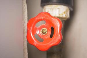 Bright red valve handle on a pipe ready to be turned for maintenance photo