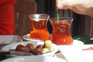Enjoying turksih tea and olives at a cozy outdoor cafe during daytime photo