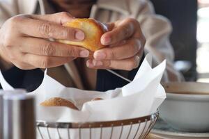 Hands breaking bread while enjoying a warm meal in a cozy cafe photo