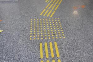 Yellow tactile guide lines on a public space floor in an urban area photo