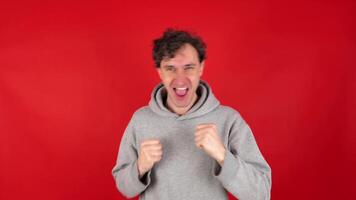 Happy man in casual making dab arms gesture on blank red studio background, funny white guy dabbing moving in internet meme pose celebrating victory having fun, dance school or triumph concept. video