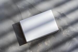 A Blank White Cardboard Box on a Grey Textured Surface photo