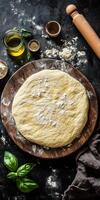 Freshly prepared dough on wooden board with rolling pin and basil for italian cooking inspiration photo