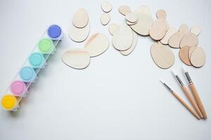 Wooden Easter egg shapes with paint and brushes with copy space for creative crafting photo