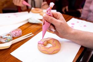 Decorating donuts with pink icing. Creative cookie design workshop photo