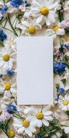 Botanical flat lay design with blank white invitation surrounded by colorful flowers for event stationery photo
