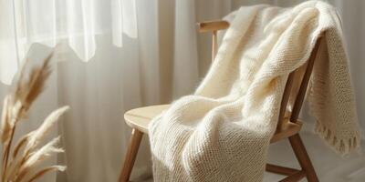 Minimalist cozy knitting scene with soft woolen blanket on wooden chair by window photo