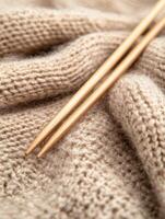 Cozy beige woolen fabric with knitting needles. Perfect for warm winter projects photo